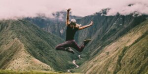 A person jumping into the air with mountains in the background