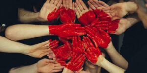 Several hands with palms facing the camera with a heart painted on them