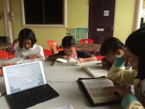 Four children reading bibles at a table