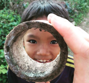 A child looking through a pipe and smiling