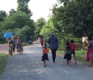 A dirt road with several people walking up and down it