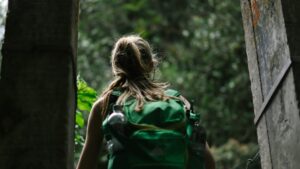 A woman walking out the door with a backpack on her back