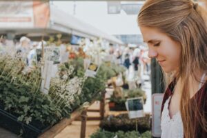 A woman looking at flowers for sale in an outdoor market