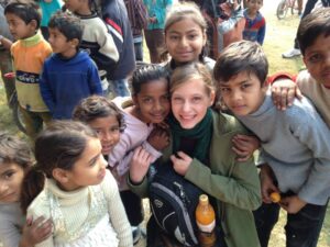 A group of children hugging a young lady while smiling for the photo
