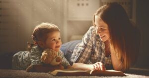A woman and child laying on their stomachs reading a book