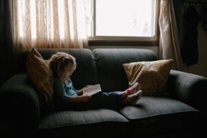 A child sitting on a couch reading a book