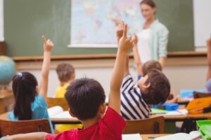 children in a classroom raising their hands