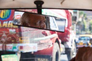 Looking out the front windshield of a vehicle with the rear-view mirror reflecting the driver