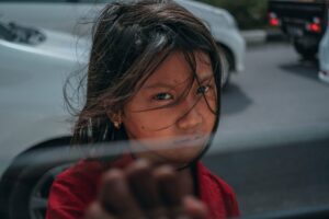 A young child standing outside the window of a vehicle looking in