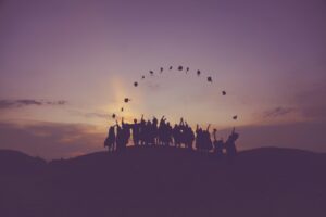 a group of people in the horizon throwing their graduation hats in the air, making a semi-circle with the hats