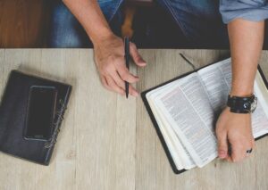 top view of a person reading a bible with a pen in their hand