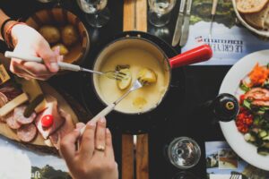 two people using forks to get food out of a pot