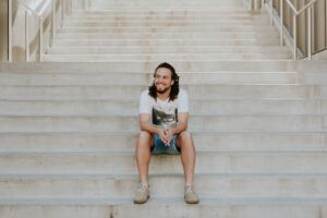 a young man sitting on steps smiling