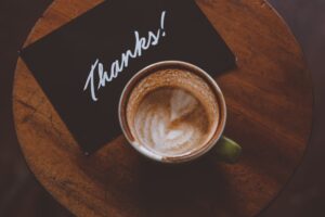 top view of a coffee cup next to a black piece of paper with the word "thanks!"