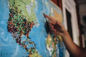 a person's hand pointing to a spot on a global map