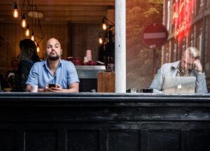 man sitting at a business holding his phone and staring in the distance