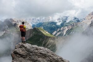 man with a backpack standing on top of a large rock looking into the misty mountains