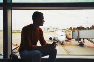 A man sitting in the window of an airport waiting for a flight