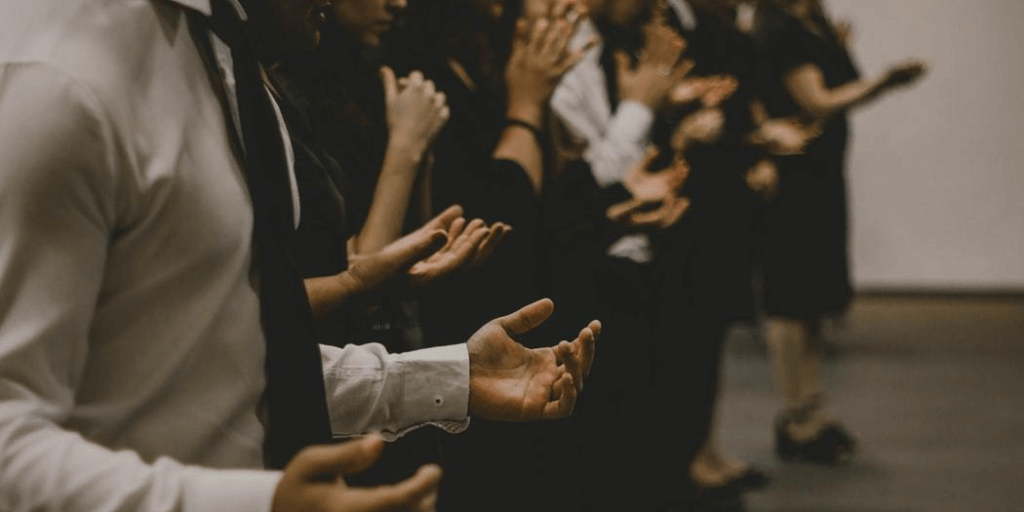 A row of people worshiping with their hands out