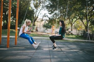 two women on swings facing each other talking